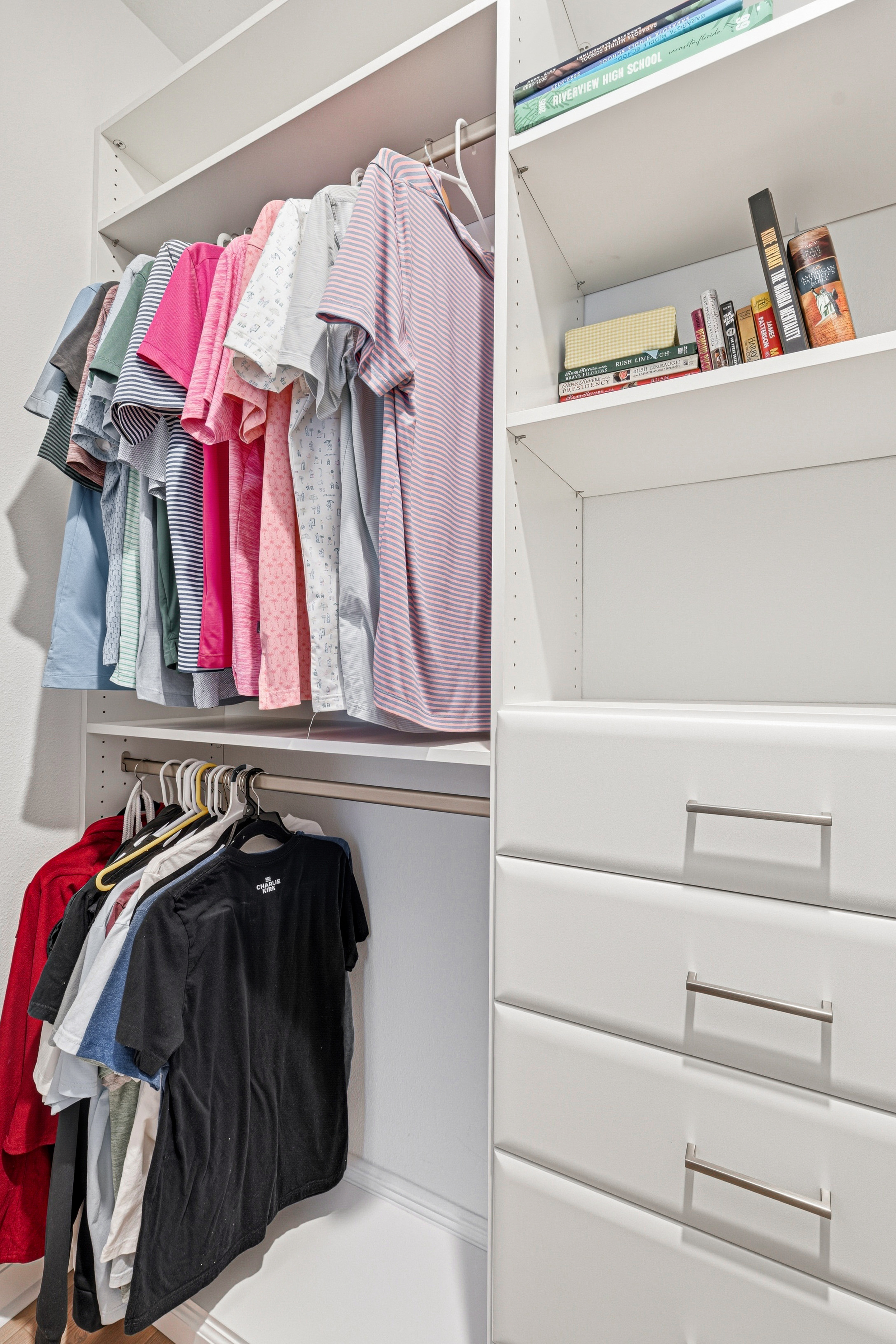 Custom closet double hang rods for colorful wardrobe with adjacent open shelves and drawers in Bradenton FL