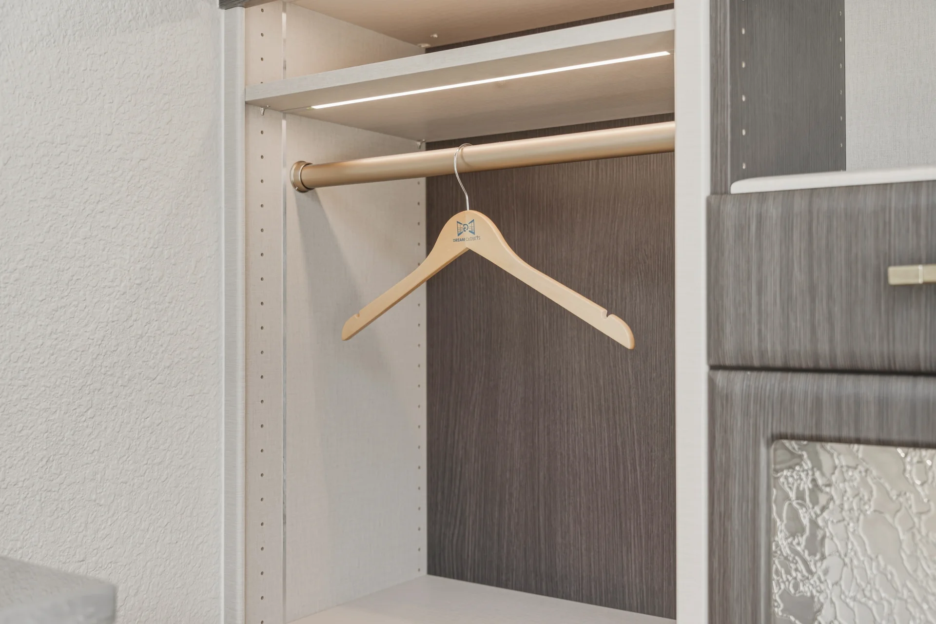 Close-up detail of premium closet hanging rod and gray wood backing at Dream Closets LLC showroom in Bradenton FL
