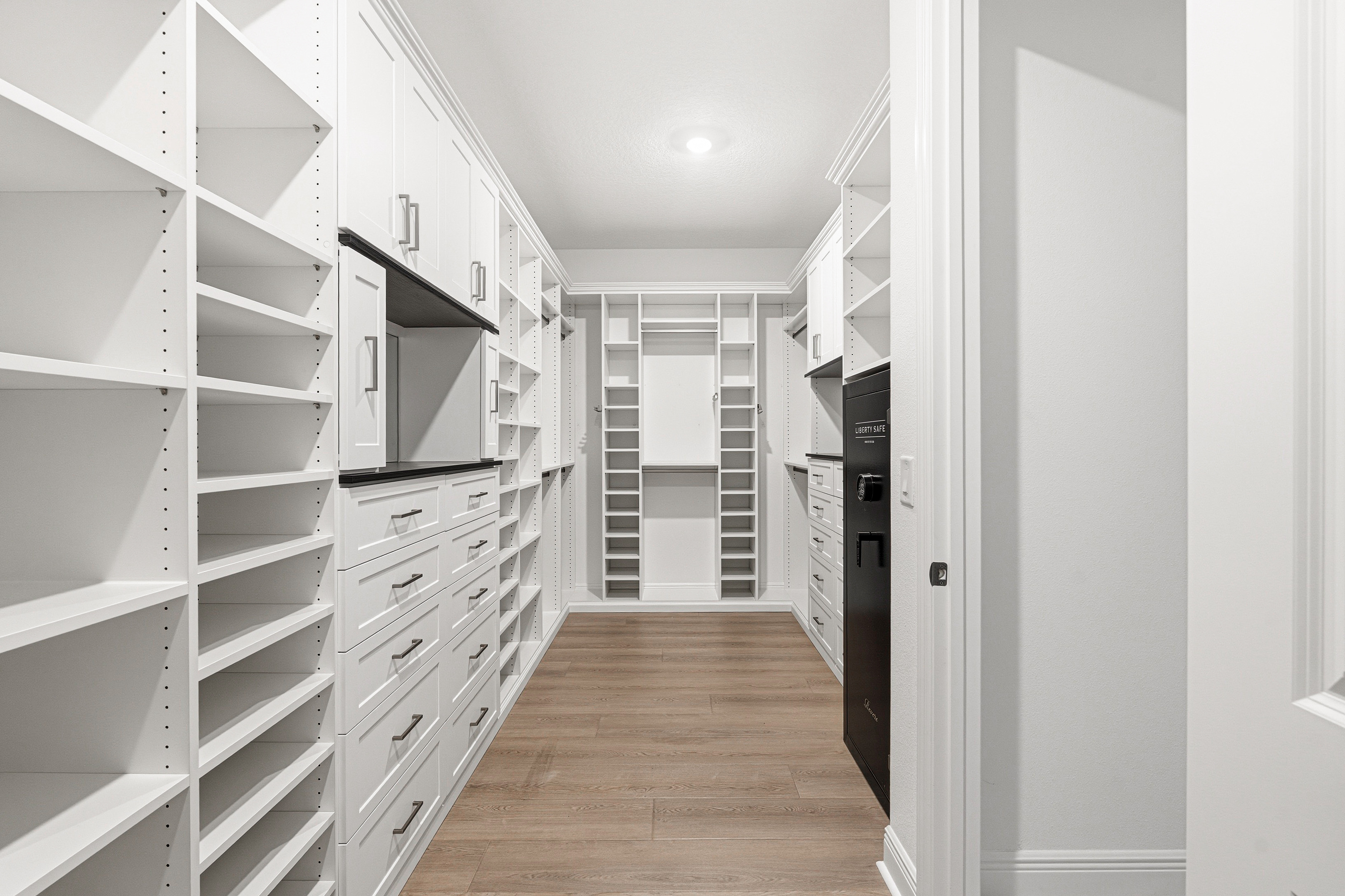 Large walk-in closet full-length hallway view with dual-wall shelving and drawer systems in Bradenton FL