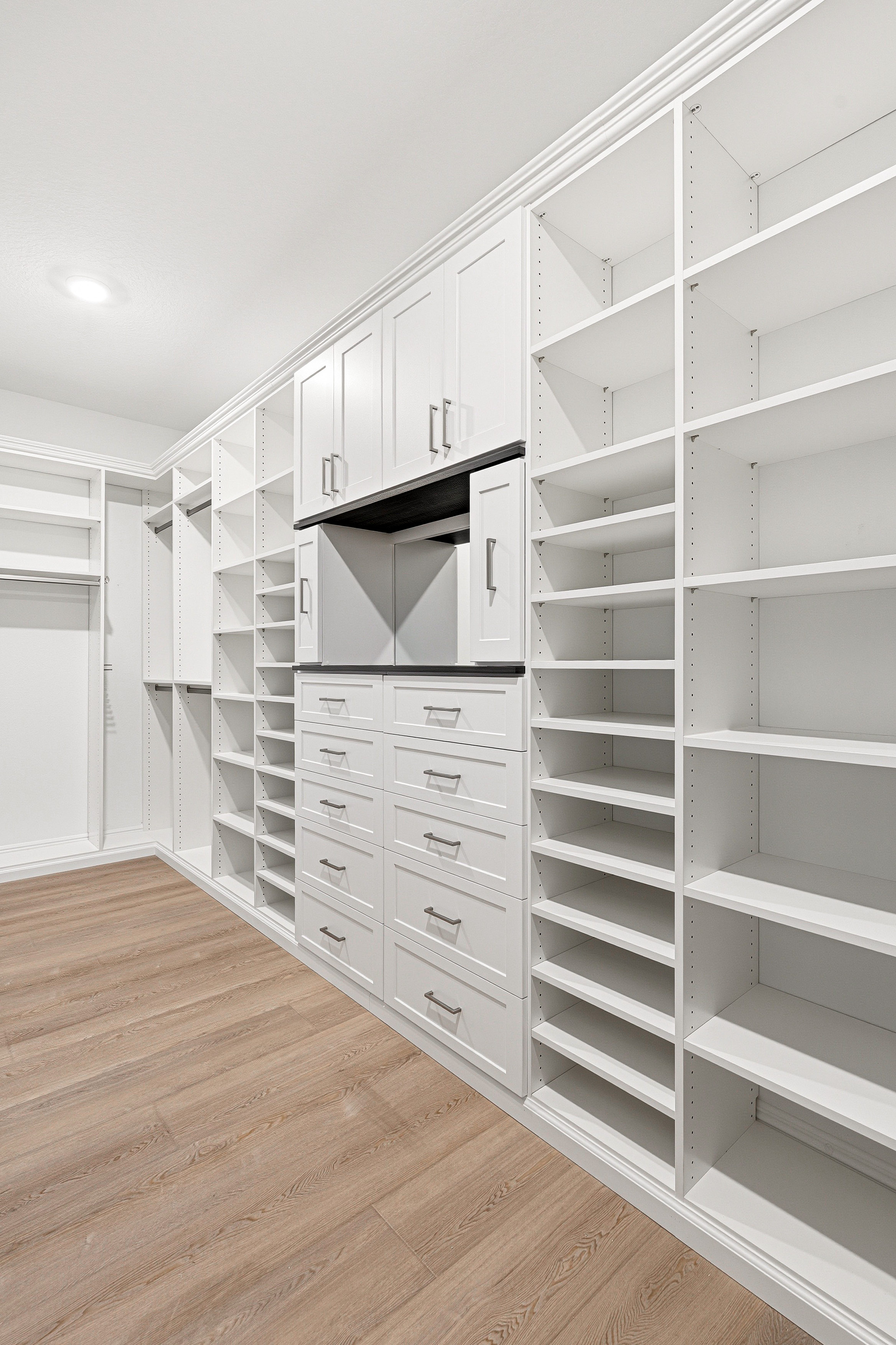 Walk-in closet with floor-to-ceiling white cabinetry, adjustable shoe shelving, and drawer tower in Bradenton FL