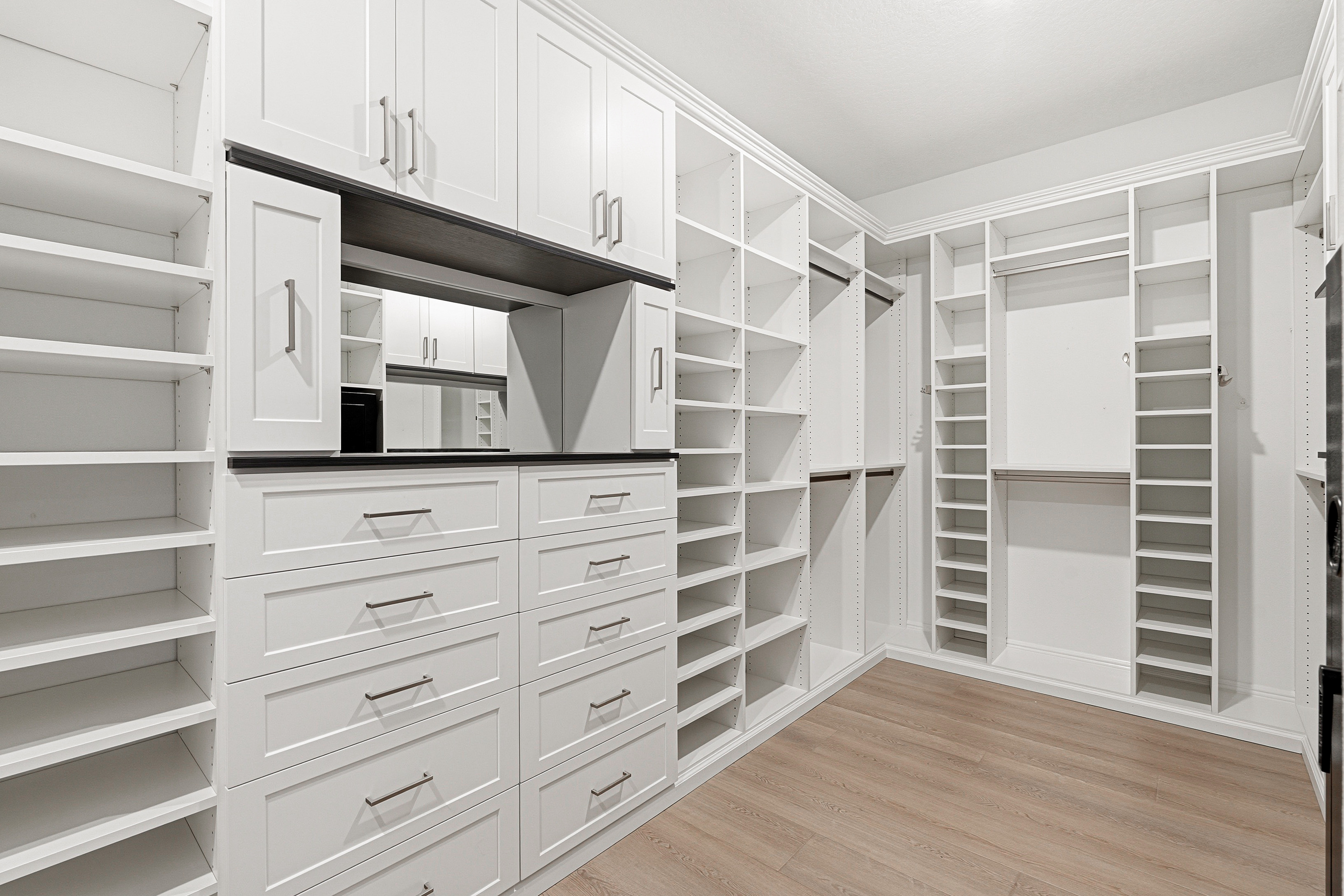 Luxury walk-in closet with upper shaker cabinets, vanity mirror, and full drawer tower in Bradenton FL