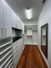 Narrow walk-in closet with upper cabinets and dark granite countertop
