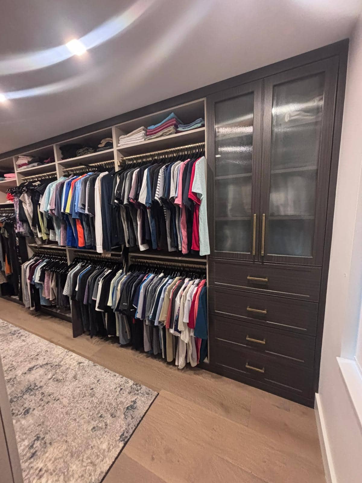Custom walk-in closet with dark cabinetry and gold hardware by Dream Closets in Longboat Key FL