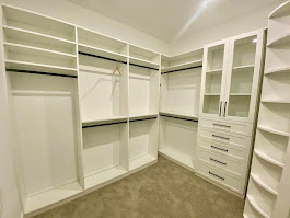 White walk-in closet with glass-front cabinets and center drawers