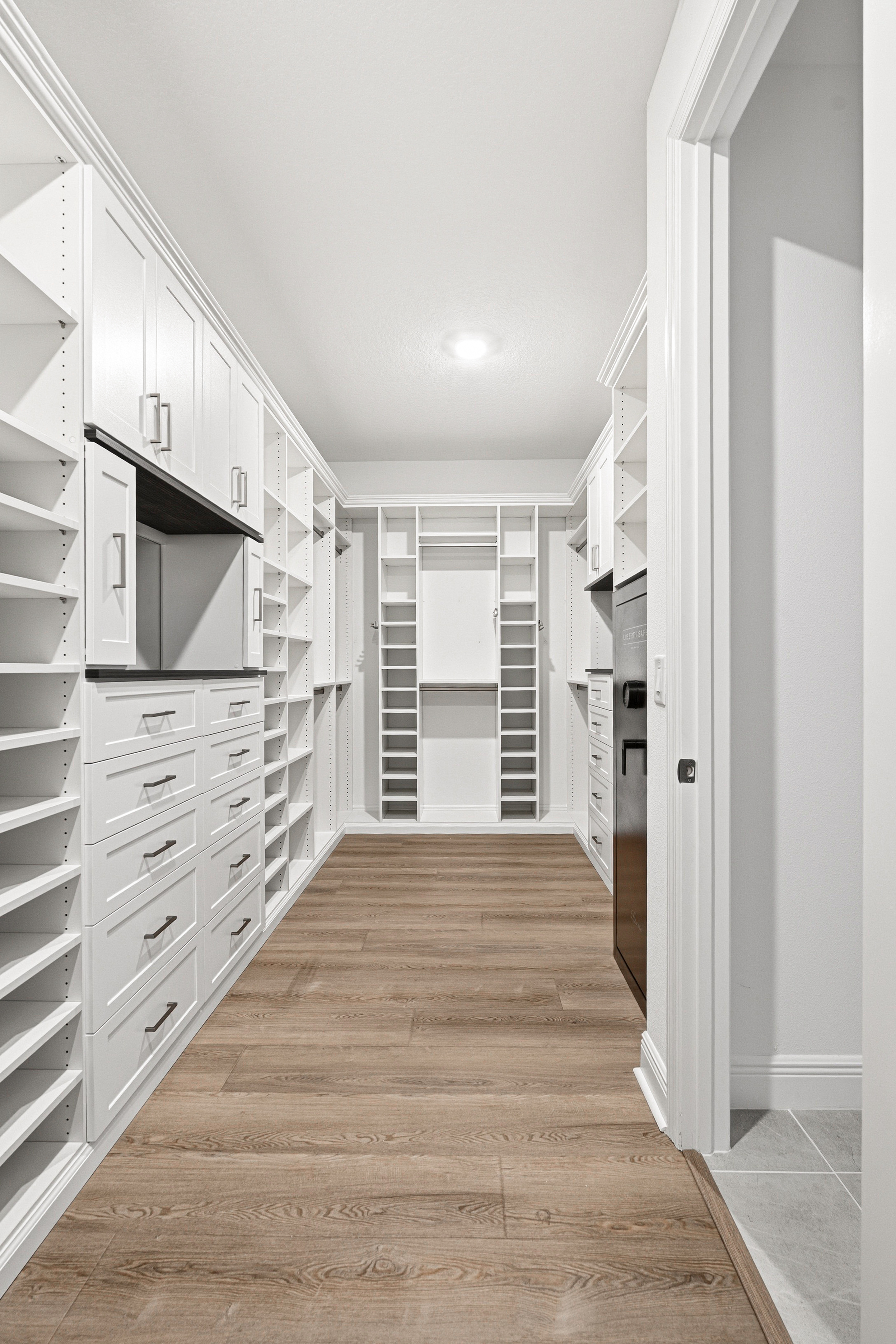 Walk-in closet hallway layout with dual-wall custom shelving, drawers, and hanging zones in Bradenton FL